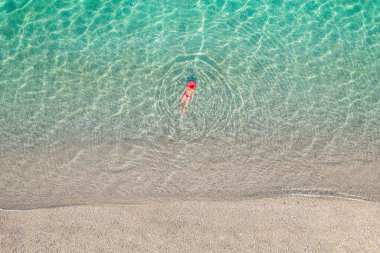 Üst Manzara. Kumsalda deniz suyunda yüzen kırmızı şapkalı ve bikinili güzel bir kadın. Drone, helikopter fotoğrafı. Yaz tatili. Yukarıdan görüntüle. 