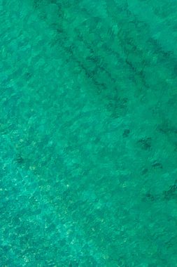 Background, texture of relaxing, calm turquoise, transparent sea water with stones, slabs, lump, coral. Summer vacation. Blue ocean lagoon. Drone, copter top view. 