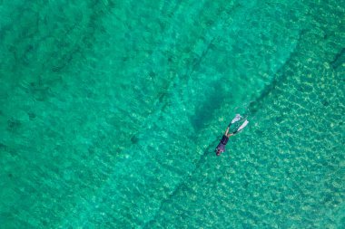Spearfishing scuba diver in tropical exotic sea, ocean turquoise clear water. Man swimming hunting exotic fish, poaching. Top view. Aerial, drone, copter view.