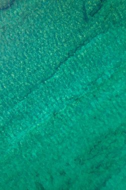 Background, texture of relaxing, calm turquoise, transparent sea water with stones, slabs, lump, coral. Summer vacation. Blue ocean lagoon. Drone, copter top view. 