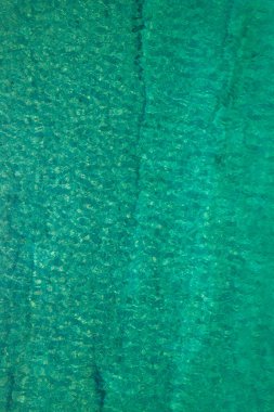 Background, texture of relaxing, calm turquoise, transparent sea water with stones, slabs, lump, coral. Summer vacation. Blue ocean lagoon. Drone, copter top view. 