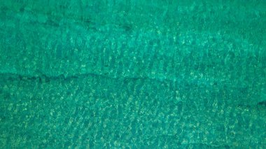 Background, texture of relaxing, calm turquoise, transparent sea water with stones, slabs, lump, coral. Summer vacation. Blue ocean lagoon. Drone, copter top view. 
