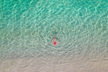 Üst Manzara. Kumsalda deniz suyunda yüzen kırmızı şapkalı ve bikinili güzel bir kadın. Drone, helikopter fotoğrafı. Yaz tatili. Yukarıdan görüntüle. 