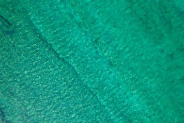 Background, texture of relaxing, calm turquoise, transparent sea water with stones, slabs, lump, coral. Summer vacation. Blue ocean lagoon. Drone, copter top view. 