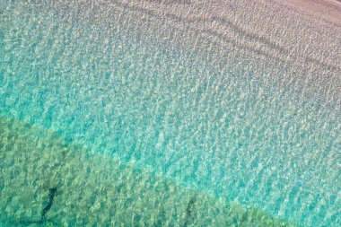 Background, texture of relaxing, calm turquoise, transparent sea water with stones, slabs, lump, coral. Summer vacation. Blue ocean lagoon. Drone, copter top view. 