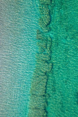 Background, texture of relaxing, calm turquoise, transparent sea water with stones, slabs, lump, coral. Summer vacation. Blue ocean lagoon. Drone, copter top view. 