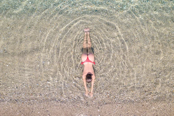 空中からの眺めだ 砂のビーチで海の水に横たわって日光浴をする赤いビキニパンティーの若い美しい女性 ドローン コッパー写真 夏休みだ 上からの眺め — ストック写真