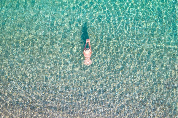 年轻美丽的女人戴着帽子 穿着白色比基尼在沙滩上的海水中游泳 无人机 复印机照片 从上面看 — 图库照片
