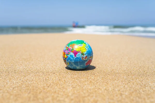 Spielzeugkugel Auf Dem Sand Des Strandes Mit Meereswellen Hintergrund Weltreisenkonzept Stockbild
