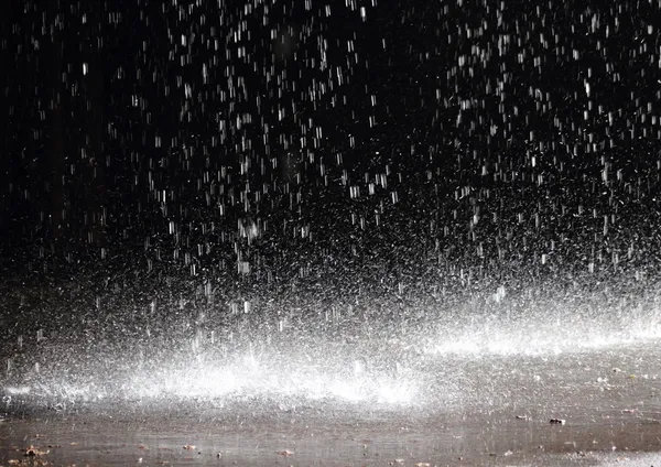 Enorme regenval op asfalt uit een gebroken goot onder een cloudbu Stockafbeelding