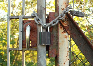 eski bir paslanmış çitin üzerinde yeni asma kilit