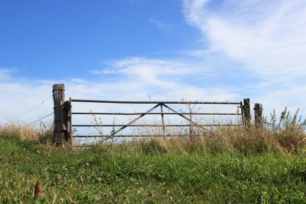 Field gate on top of a hill with blue sky — Stock Photo, Image