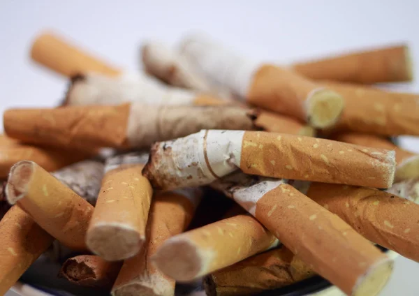 Cenicero lleno de colillas de cigarrillo usadas sobre fondo blanco —  Fotos de Stock