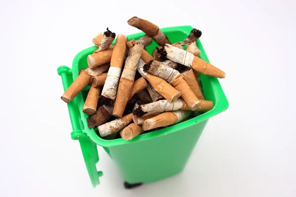 Colillas de cigarrillo usadas en la papelera verde sobre fondo blanco —  Fotos de Stock