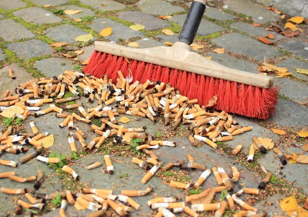 Sweeping a lot of cigarette butts from stone road — Stock Photo, Image