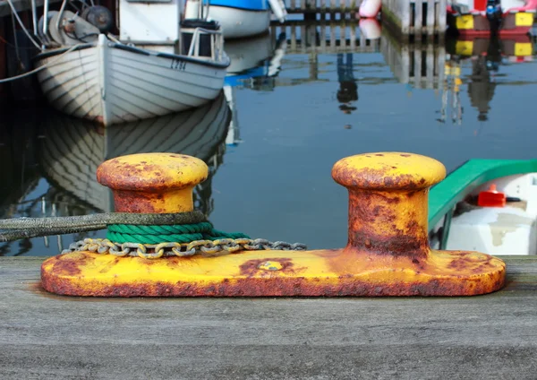 Metal bollard at small fishing harbor with ropes and chain — Stock Photo, Image