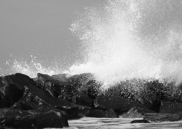 Vagues écrasantes contre des rochers noirs sur la côte — Photo