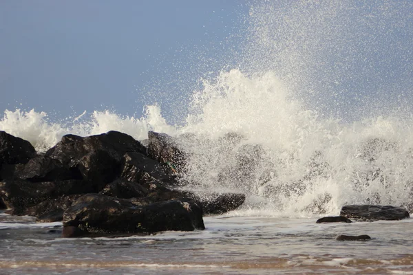 Onde d'urto contro rocce nere sulla costa — Foto Stock