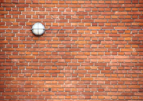 Parede de tijolo vermelho com lâmpada exterior e cabo — Fotografia de Stock