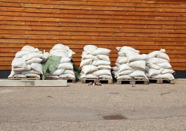 Bolsas de arena en cinco pilas con pared de madera en el fondo — Foto de Stock