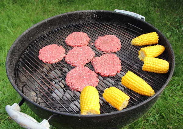 Barbecue grill met rundvlees hamburger en maïskolf Rechtenvrije Stockfoto's