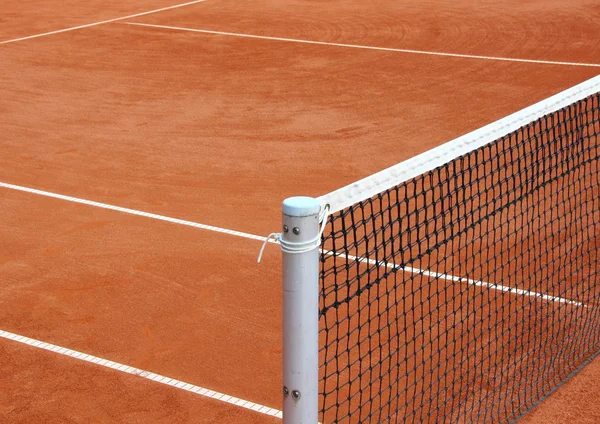Теннисная сетка на пустом красном гравии — стоковое фото