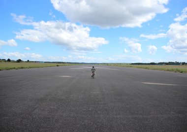 Biking child with helmet on airplane runway clipart