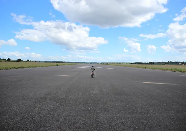 Criança de bicicleta com capacete na pista do avião — Fotografia de Stock