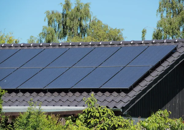 Mavi gökyüzü ile evin çatısında güneş enerjisi sistemleri