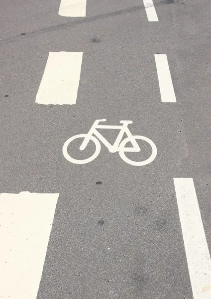 Вертикальный велосипедный знак на асфальте с белыми полосами — стоковое фото