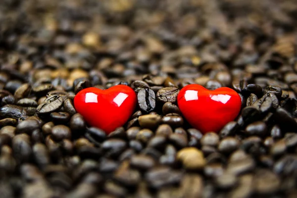 Dos corazones rojos en granos de café — Foto de Stock