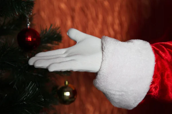 圣诞老人戴着白色手套的手放在圣诞树的后面 圣诞老人的手势 后续行动 — 图库照片