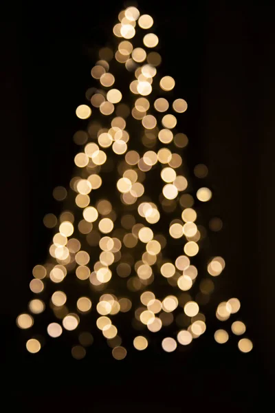 Siyah arka plandaki noel ağaçlarına odaklanmamış Noel ışıkları. Karanlık bir arka planda parlayan ışıklardan yapılmış bir Noel ağacı.
