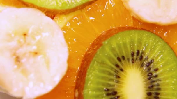 Slices van sinaasappel, kiwi, banaan bovenaanzicht. Snijwonden van verschillende vruchten spinnen. — Stockvideo
