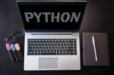 Metin pitonlu dizüstü bilgisayarın üst görüntüsü. Dizüstü bilgisayar ekranında ve klavyede Python yazıları var. Python programlama dili, bilgisayar kursları, eğitim öğrenin. 
