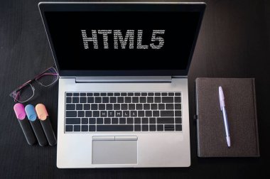HTML5 yazısıyla dizüstü bilgisayarın üst görüntüsü. Dizüstü bilgisayar ekranında ve klavyede Html5 yazıları var. html dilini, bilgisayar kurslarını, eğitimi öğren. 