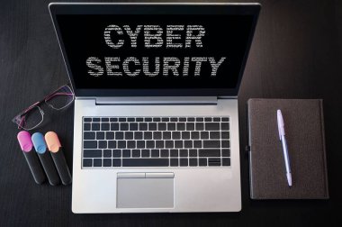 Siber güvenlikli dizüstü bilgisayarın üst görüntüsü. Bilgisayar ekranında ve klavyede siber güvenlik yazıları.