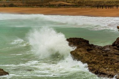 Kızgın turkuaz yeşil renk okyanus boyunca yuvarlanan dalgaların büyük kıvrımlı kıvrımları. Vahşi dalgalar fırtınalı bir günde Chabahar kıyılarını vuruyor bulutlu gökyüzü kıyıya yakın, Umman Denizi