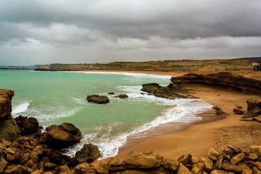 Kızgın turkuaz yeşil renk okyanus boyunca yuvarlanan dalgaların büyük kıvrımlı kıvrımları. Vahşi dalgalar fırtınalı bir günde Chabahar kıyılarını vuruyor bulutlu gökyüzü kıyıya yakın, Umman Denizi