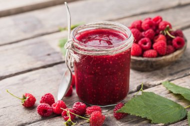 Ahşap arka planda ev yapımı ahududu reçeli, taze ahududu ve seçici bir odak noktası var..