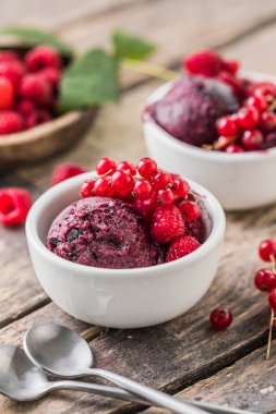 Lezzetli ve romantik bir tatlı. Ahşap arka planda beyaz bir fincanda taze böğürtlenli ev yapımı ahududu morsu topu. Kapat.