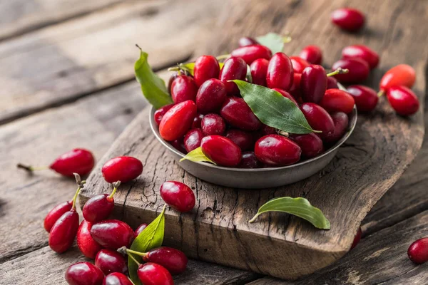 Ahşap bir arka planda, tabakta bir köpek ahşabı. Yaz hasadını topluyorum. Kırmızı çilek.