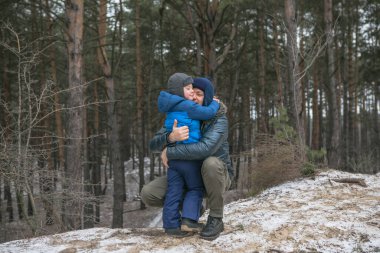 Mutlu bir aile, güneşli kış ormanlarında, Noel tatillerinde, baba ve oğul birlikte oynuyorlar.