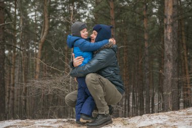 Mutlu bir aile, güneşli kış ormanlarında, Noel tatillerinde, baba ve oğul birlikte oynuyorlar.