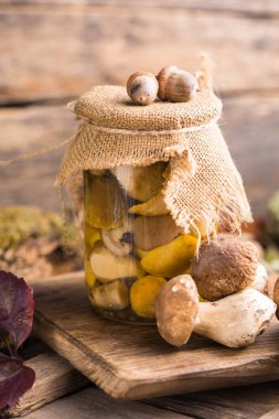 Ahşap arka planda cam kavanozlarda yenebilir mantar boletusu. Güneş ışığında kırsal ahşap masanın üzerinde camdan yapılmış mantarlar..