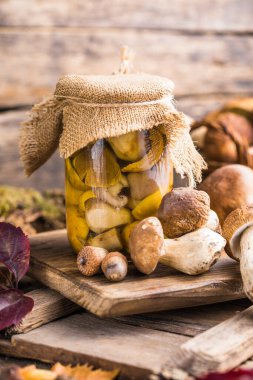 Ahşap arka planda cam kavanozlarda yenebilir mantar boletusu. Güneş ışığında kırsal ahşap masanın üzerinde camdan yapılmış mantarlar..