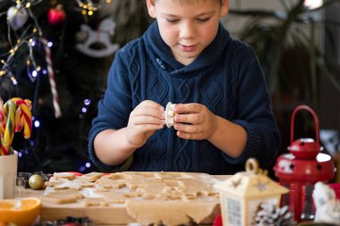 Küçük tatlı çocuk Noel kurabiyelerini yeni yıl mutfağında yapıyor..