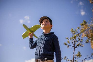 Küçük çocuk elinde oyuncak uçakla oynuyor. Mutlu Çocuk dışarıda parkta oynuyor.