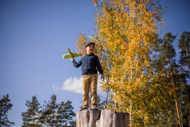 Küçük çocuk elinde oyuncak uçakla oynuyor. Mutlu Çocuk dışarıda parkta oynuyor.