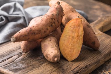 Tahta arka planda tatlı patates, yakın plan. Çiğ patates ya da otlu yarasa.